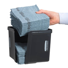 A hand inserts quarter-folded wipes into the gray Kimberly-Clark Professional™ wipe dispenser from Kimberly-Clark GmbH - for hygienic cloth removal. The neatly folded wipes and the front label are visible.