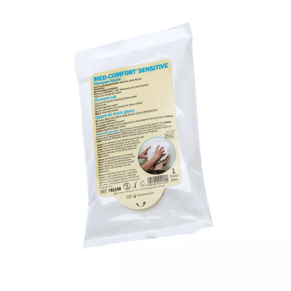 A white plastic packaging with the inscription “Med-Comfort Shampoo Cap with Nourishing Conditioner” from AMPri Handelsgesellschaft mbH. On the front, you will find instructions and details in several languages. Ideal for the care of bedridden people, it contains a single-use Med-Comfort shampoo cap that ensures a hygienic hair wash. The background is white.