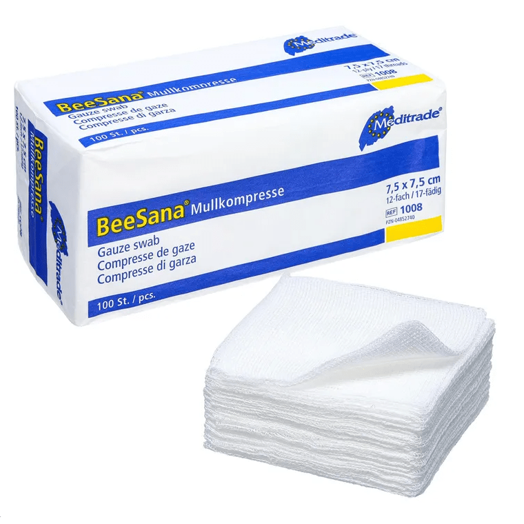The image shows a box labeled “Meditrade BeeSana® gauze compress, non-sterile” next to a stack of white gauze compresses, ideal for effective wound care. The box measures 7.5 x 7.5 cm and contains 100 pieces. These gauze compresses are neatly stacked in front of the box, manufactured by Meditrade GmbH.