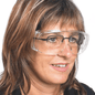 A person with shoulder-length hair is wearing a transparent Mediware protective eyewear made of polycarbonate from Servoprax GmbH over regular glasses. They are looking slightly to the side against a plain white background.