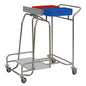 The Novocal stainless steel laundry collector "Compact plus" dual combi collector features a stainless steel frame, four wheels, and holds two rectangular containers - red and blue - for efficient laundry sorting.