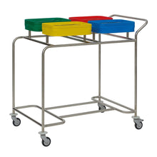 The Novocal stainless steel laundry collector "Compact plus" fourfold collector features a stainless steel frame, four wheels, a handle, and holds four colored containers (green, yellow, red, blue) for dirty laundry - each container with a slot at the top.