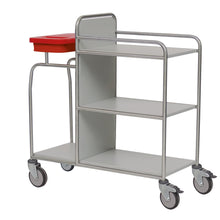 The durable Novocal station cart made of stainless steel with three shelves, four wheels, and a red plastic container on the top left is empty and depicted on a white background. All pipe connections are welded all around.