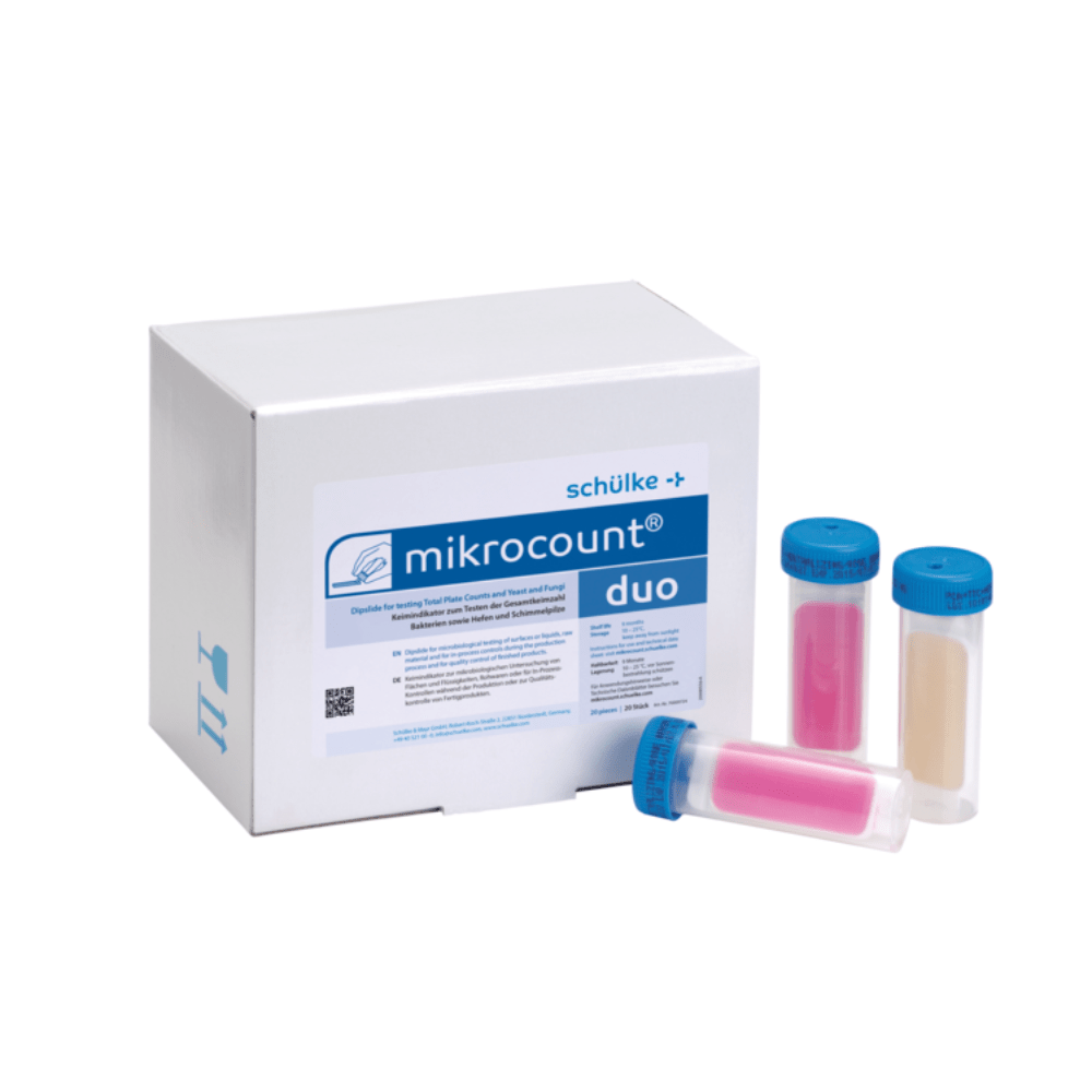 The image shows a box labeled “Schülke mikrocount® duo, germ indicator | Pack (20 pieces)” from the brand “Schülke & Mayr GmbH” next to three color-coded tubes with blue caps. The tubes contain pink and beige substances used to detect microorganisms on surfaces and in liquids, including yeasts and molds.