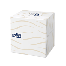 A Tork 140278 Tork extra soft tissue dispenser cube in white with a wavy beige pattern and the TORK logo on the side.