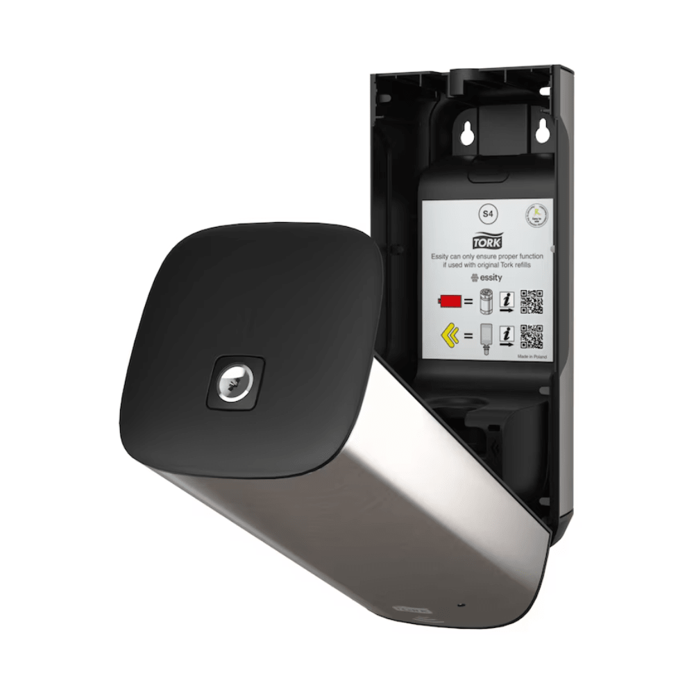 The Tork 460009 Skincare Dispenser from TORK – Essity Professional Hygiene Germany GmbH is openly presented and features a stylish, modern design with a metallic surface and a black front panel. Inside, operating instructions and QR codes are visible. This wall-mounted stainless steel dispenser is designed for efficient towel use and features innovative Intuition Sensor technology.