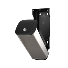 A Tork 460010 dispenser for soap and hand sanitizers in stainless steel and black from Essity Professional Hygiene Germany GmbH for wall mounting with an open front panel that reveals the interior compartment. This modern design also features a partially detached plate that exposes the interior bracket and screw positions.