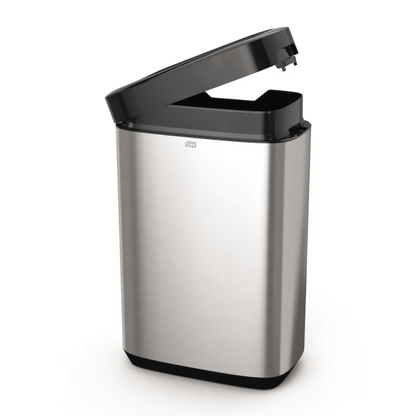 The Tork 460011 Tork Waste Bin from the Image Line series by TORK – Essity Professional Hygiene Germany GmbH features a slightly open stainless steel design with a black sensor-activated lid. Its sleek stainless steel design offers a capacity of 50 liters and a rectangular shape with a smooth surface, ideal for modern spaces.
