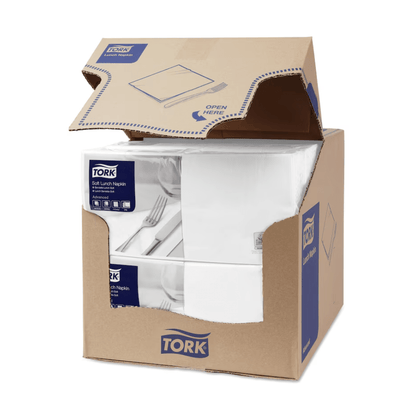 A carton of Tork 477414 Soft Lunch Napkins White Advanced 3-ply is partially open, revealing four stacks of three-ply, industrially compostable white napkins. The carton displays the blue and white TORK branding - Essity Professional Hygiene Germany GmbH, along with product information and a clear 'Open here' instruction on the top flap.