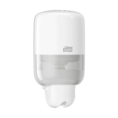 The Tork 561000 Mini Dispenser for Liquid Soap Elevation S2 from TORK - Essity Professional Hygiene Germany GmbH is a modern, white wall-mounted soap dispenser. It features a sleek design with a transparent lower part to display the liquid soap level, and the brand logo adorns the upper half.