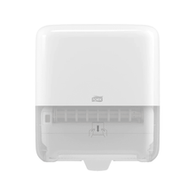 A white, wall-mounted Tork Matic® 551000 dispenser for roll towels Elevation H1 with a transparent bottom for easy level indication. The front features the TORK logo – Essity Professional Hygiene Germany GmbH, as well as a diagram showing how to pull out the roll towels.