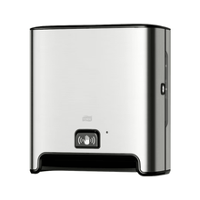 A TORK Tork Matic® 460001 sensor dispenser for roll towels Image Line made of stainless steel for wall mounting with sensor H1 | Pack (1 piece) with black base and sensor display symbol on the front. This dispenser, designed for touch-free single sheet dispensing, features a modern, simple appearance and uses roll towels to ensure a hygienic experience.