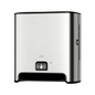 A TORK Tork Matic® 460001 sensor dispenser for roll towels Image Line made of stainless steel for wall mounting with sensor H1 | Pack (1 piece) with black base and sensor display symbol on the front. This dispenser, designed for touch-free single sheet dispensing, features a modern, simple appearance and uses roll towels to ensure a hygienic experience.