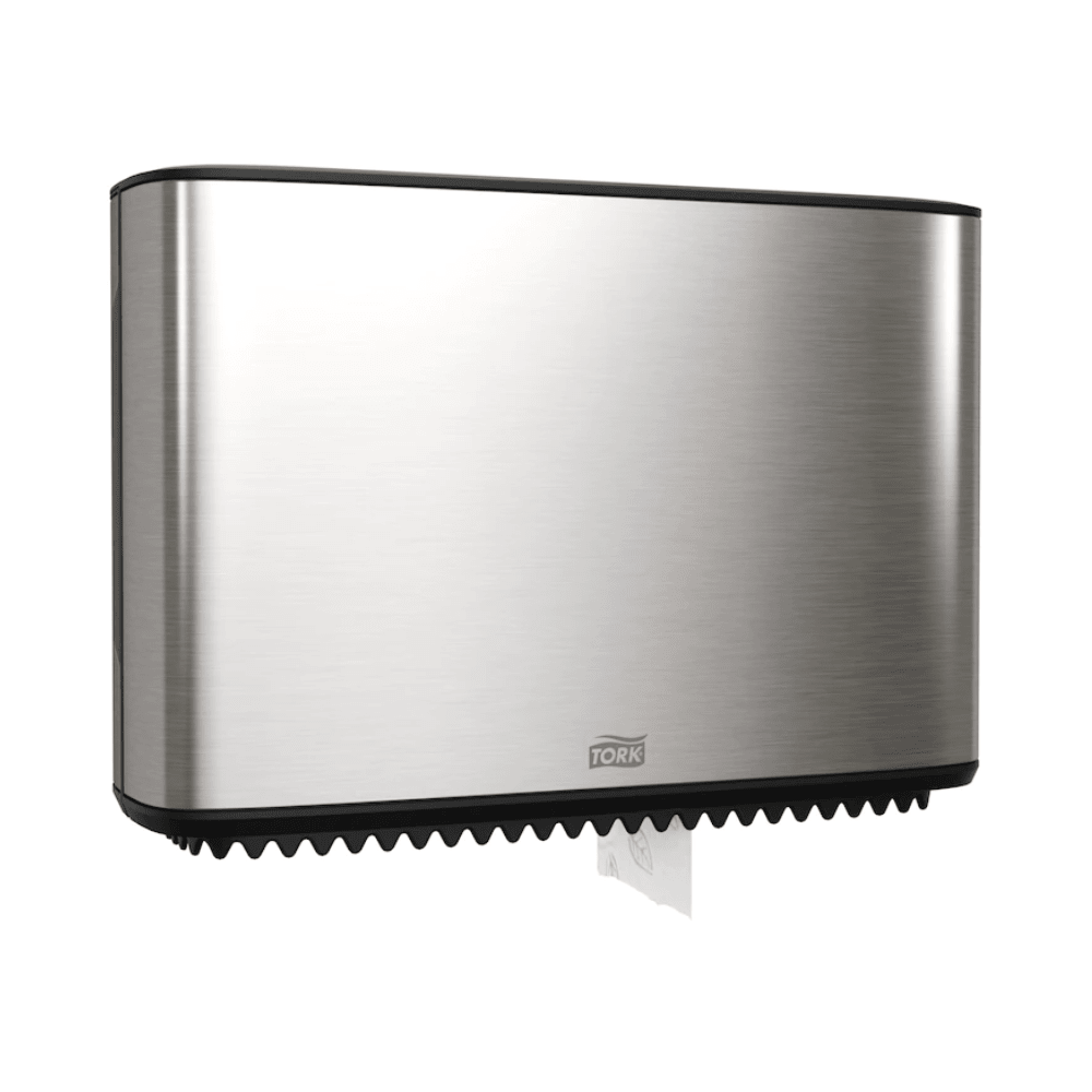A Tork Xpress dispenser for mini-jumbo toilet paper, part of the Image Line, is elegantly mounted on the wall. This stainless steel dispenser has a sleek rectangular design, with a small section of white paper visible at the bottom. The brand "TORK – Essity Professional Hygiene Germany GmbH" is clearly visible on the front.