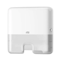 A Tork Xpress® 552100 Mini Dispenser for Multifold Hand Towels Elevation H2, manufactured by TORK – Essity Professional Hygiene Germany GmbH, is wall-mounted. It features a simple rectangular design with rounded edges, a visible lock on the right side, and an opening at the bottom for single sheet dispensing of multifold towels.