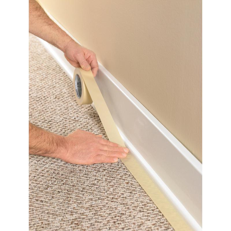 A person uses the Scotch® Classic masking tape, 24 mm x 50 m (70% PEFC) from 3M Deutschland GmbH, to tape off the baseboard where the carpet meets the wall, to protect the trim during painting and renovation work.