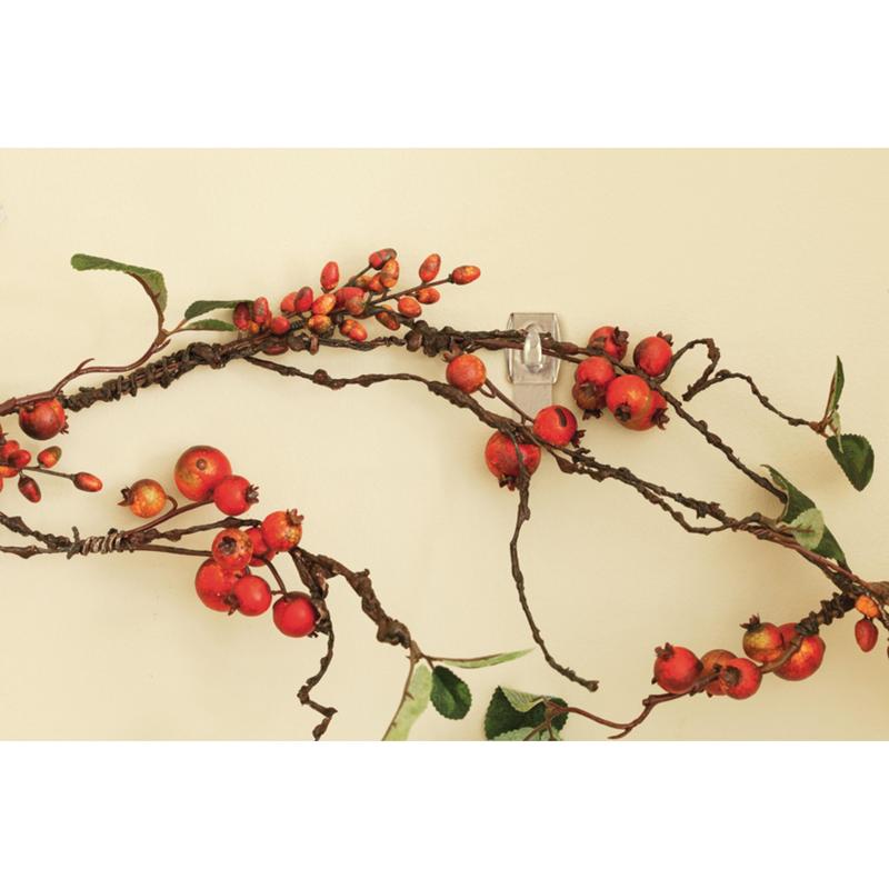 A decorative branch with red berries and green leaves hangs on a beige wall, supported by the Command™ Mini Hook, transparent, with transparent strips, 17006CLRFGN by 3M Deutschland GmbH - perfect storage without drilling.
