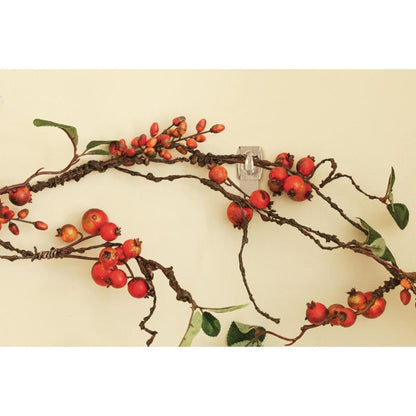 A decorative branch with red berries and green leaves hangs on a beige wall, supported by the Command™ Mini Hook, transparent, with transparent strips, 17006CLRFGN by 3M Deutschland GmbH - perfect storage without drilling.