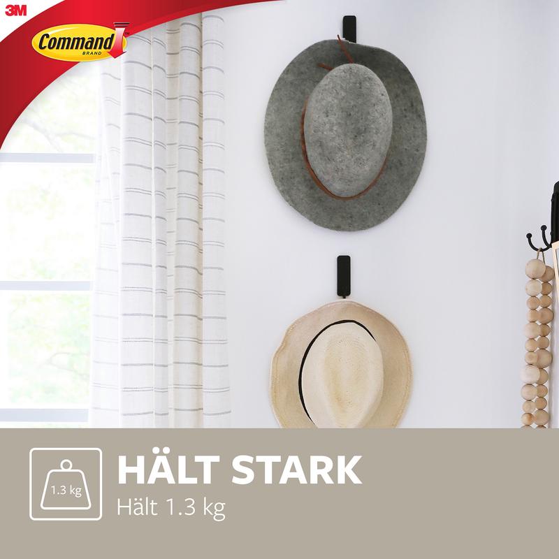 Two hats, one gray and one beige, hang on a 3M Medium-sized Command™ matte black hook (17034B) next to a window with white curtains. These wall hooks from 3M hold up to 1.3 kg and protect your walls.