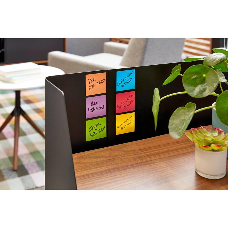 A black office partition displays six colorful Post-it® Super Sticky Notes (76mm x 76mm, 90 sheets/block, 100% PEFC) from 3M Deutschland GmbH with handwritten notes, next to a wooden desk and a green potted plant.