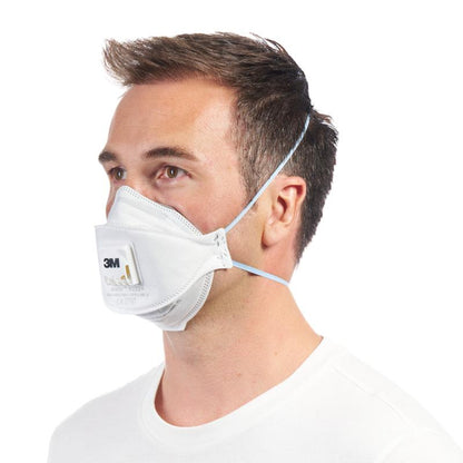 A man wears the 3M™ Aura™ Comfort Cool Flow™ Particulate Respirator 9332+ FFP3 with valve from 3M Deutschland GmbH, secured with two elastic bands, from the left against a solid white background.