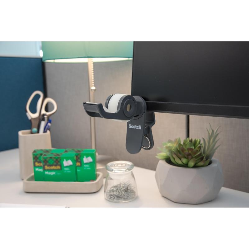 On the desk: a 3M Scotch™ Clip & Twist Tape Dispenser with Scotch® Magic™ Invisible Tape (19 mm × 8.89 m), a lamp, scissors in a holder, two additional rolls of Scotch® tape, a jar with pins, and a small potted succulent plant.