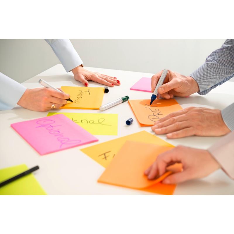 Three people are writing on 3M Post-it® Super Sticky Notes in large format, lined (101 x 152 mm), from 3M Deutschland GmbH. On the white table are colorful notes with words like "Optional" and uncapped markers.