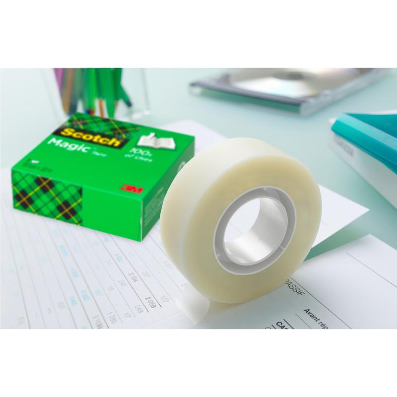 A roll of 3M Deutschland GmbH Scotch® Magic™ Invisible Tape (19 mm x 33 m) from the value pack with 24 rolls is being unrolled on paper, while the green box with the inscription "Value pack, 24 pieces" stands among office supplies.